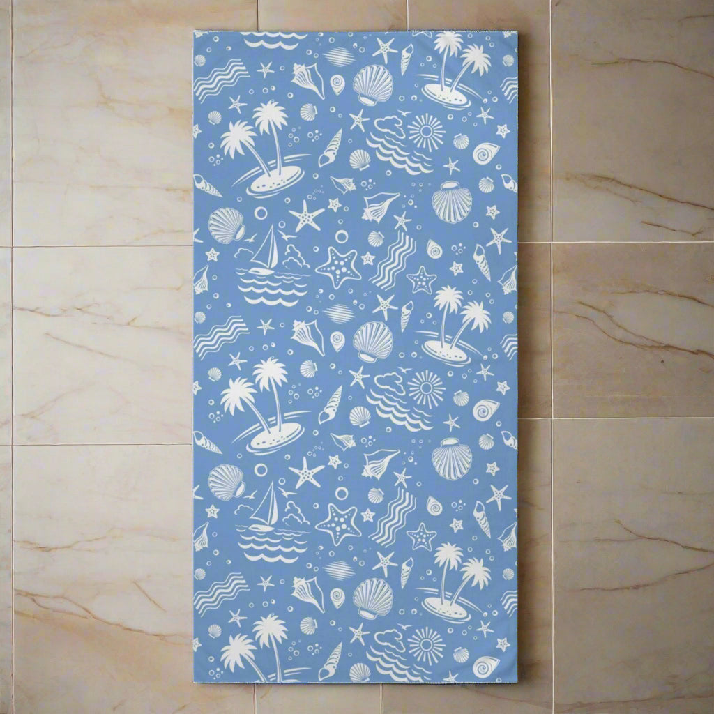 Blue tropical beach towel with white nautical and beach-themed patterns, soft mink-cotton blend, ideal for summer and pool days