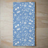 Blue tropical beach towel with white nautical and beach-themed patterns, soft mink-cotton blend, ideal for summer and pool days