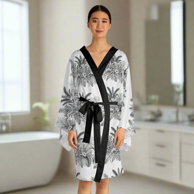 Woman wearing chic long sleeve floral kimono robe with black trim and belt in bright modern bathroom
