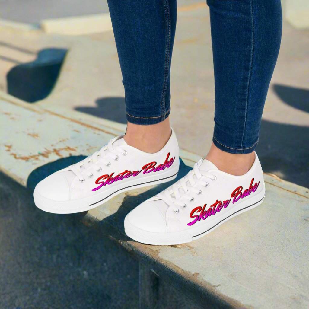 Women's Low Top Sneakers with Skater Babe lettering in pink and purple, designed by Leanne Roberts, on white canvas with blue jeans.