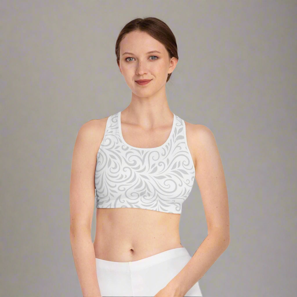 Woman wearing a white patterned sports bra and white pants on a white background