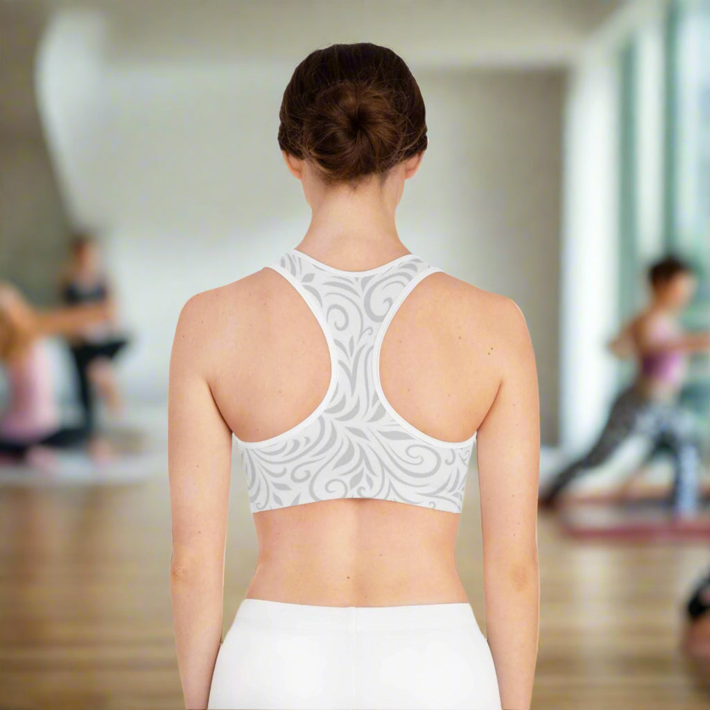 Woman wearing a light gray sports bra with intricate patterns on a white background